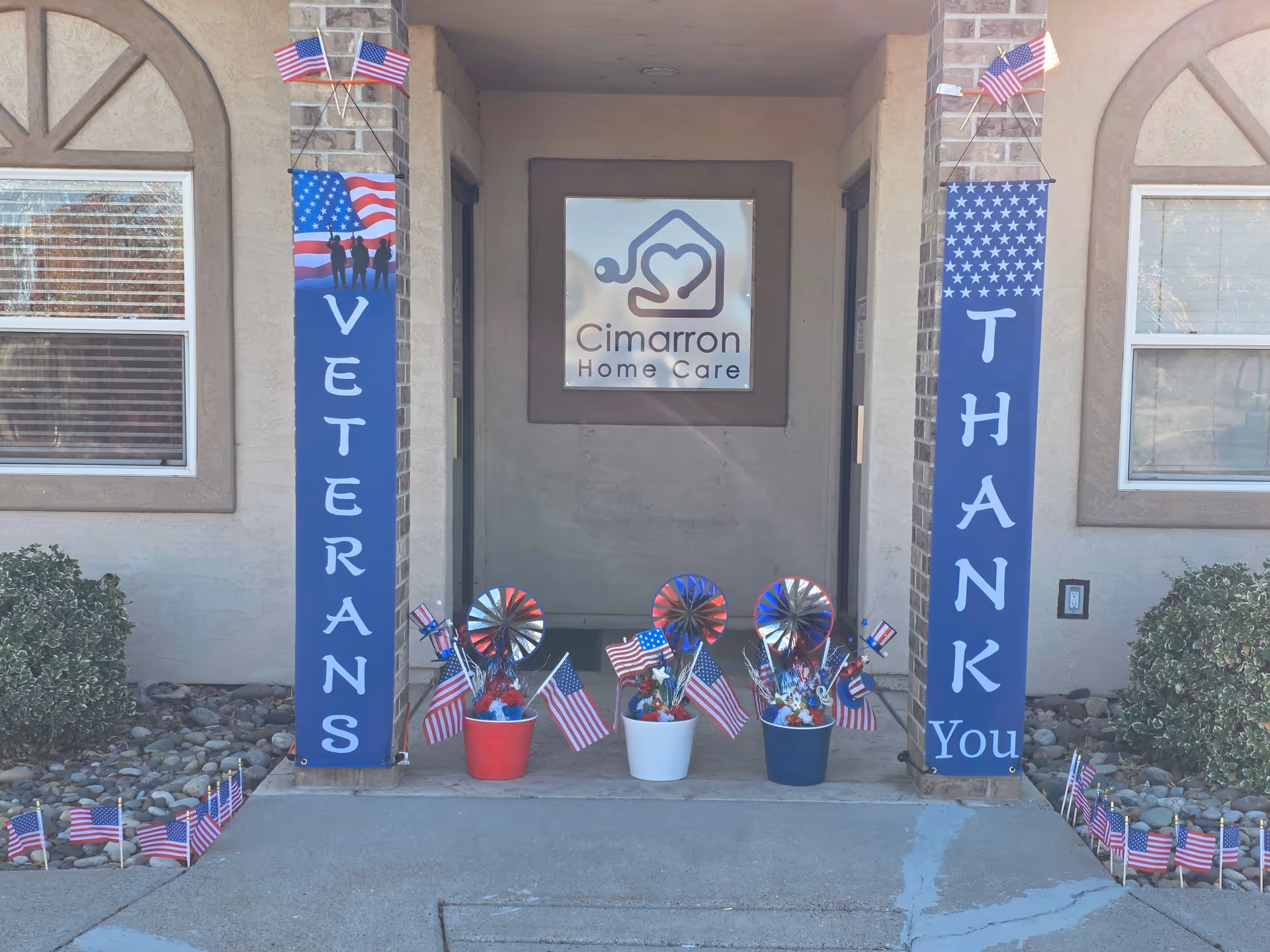 Entrance of Cimarron Home Care with patriotic banners, flags, and decorative buckets.