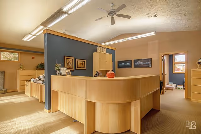 Reception desk in a senior living facility lobby with beige walls and a blue accent partition