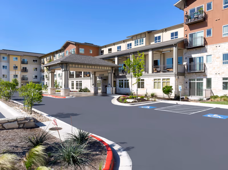 Exterior view of Affinity at Wells Branch senior living facility with entrance canopy and parking lot.