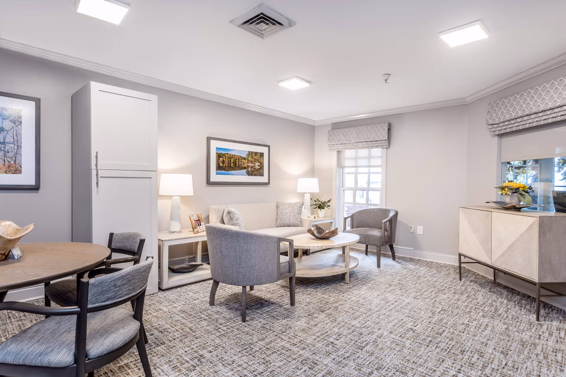 Bright, contemporary senior living lounge with seating, coffee table, lamps, and artwork.