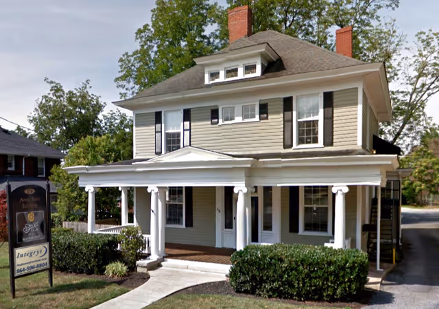Two-story beige building with a white-columned front porch and a sign for Integrys Home Caregiving.