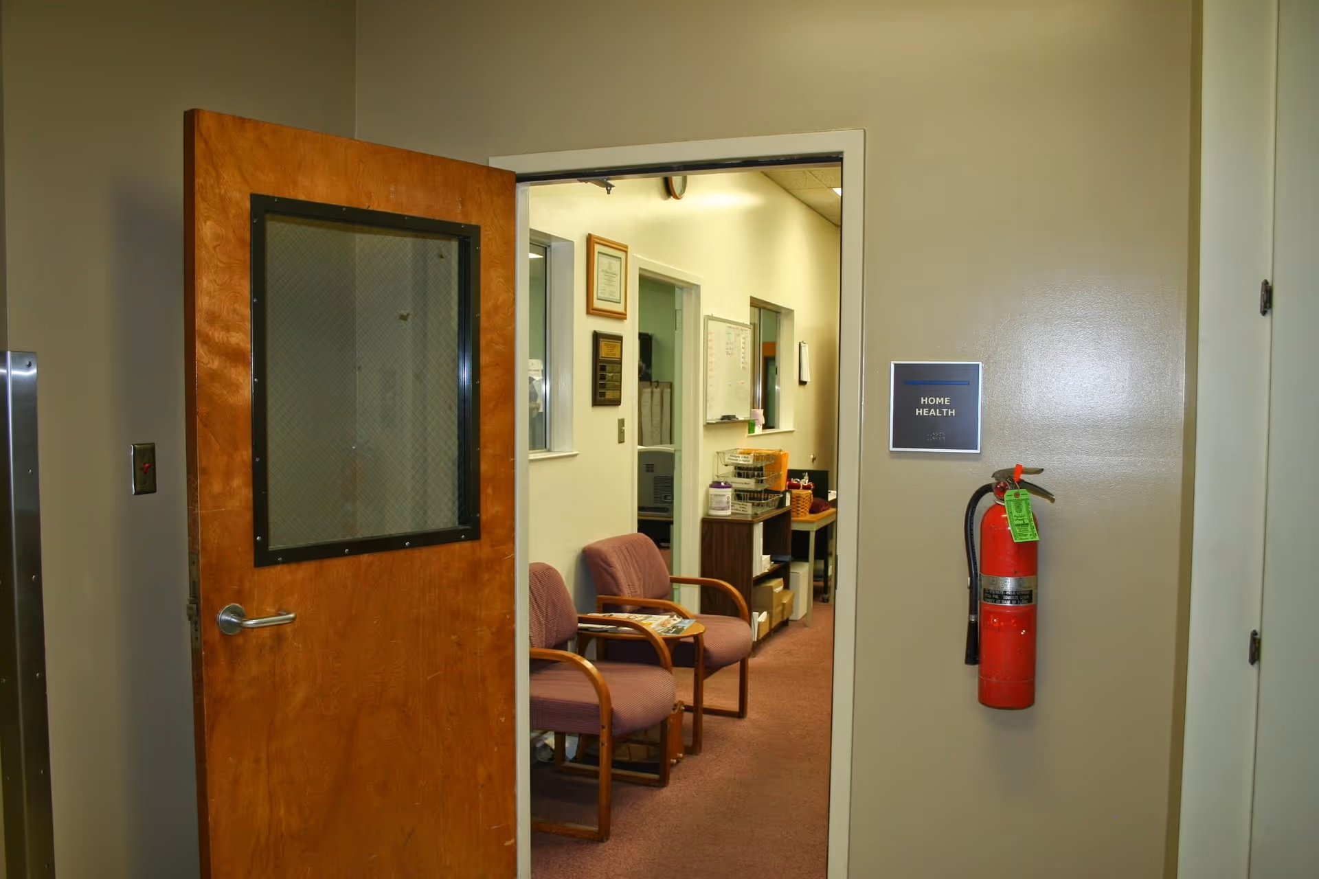 Open door reveals a small waiting area with purple chairs and a hallway.