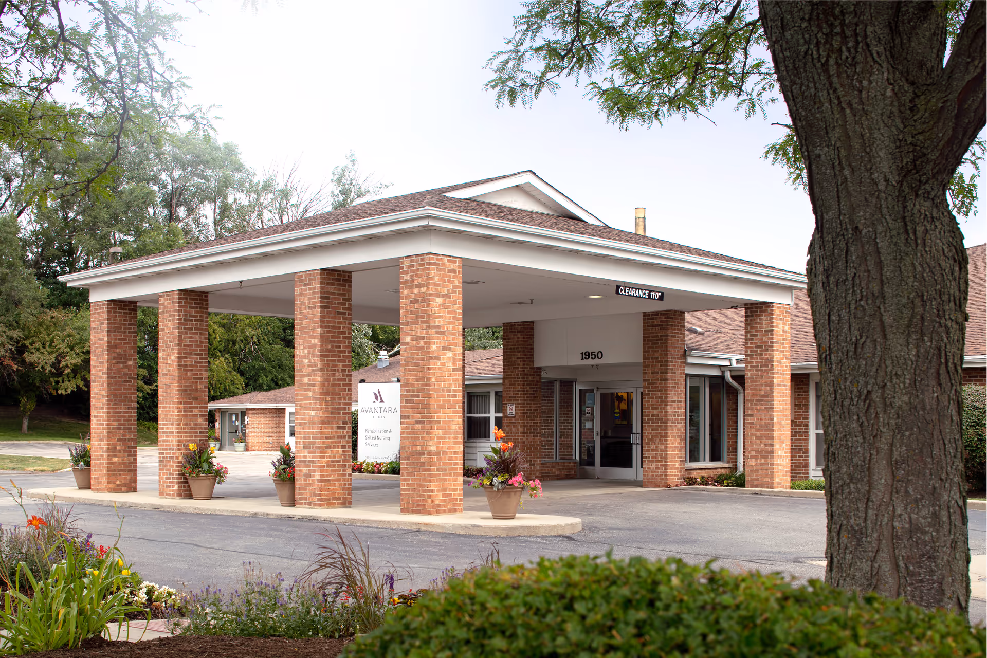 Entrance to Avantara Elgin, a brick senior living facility, with a large covered canopy.