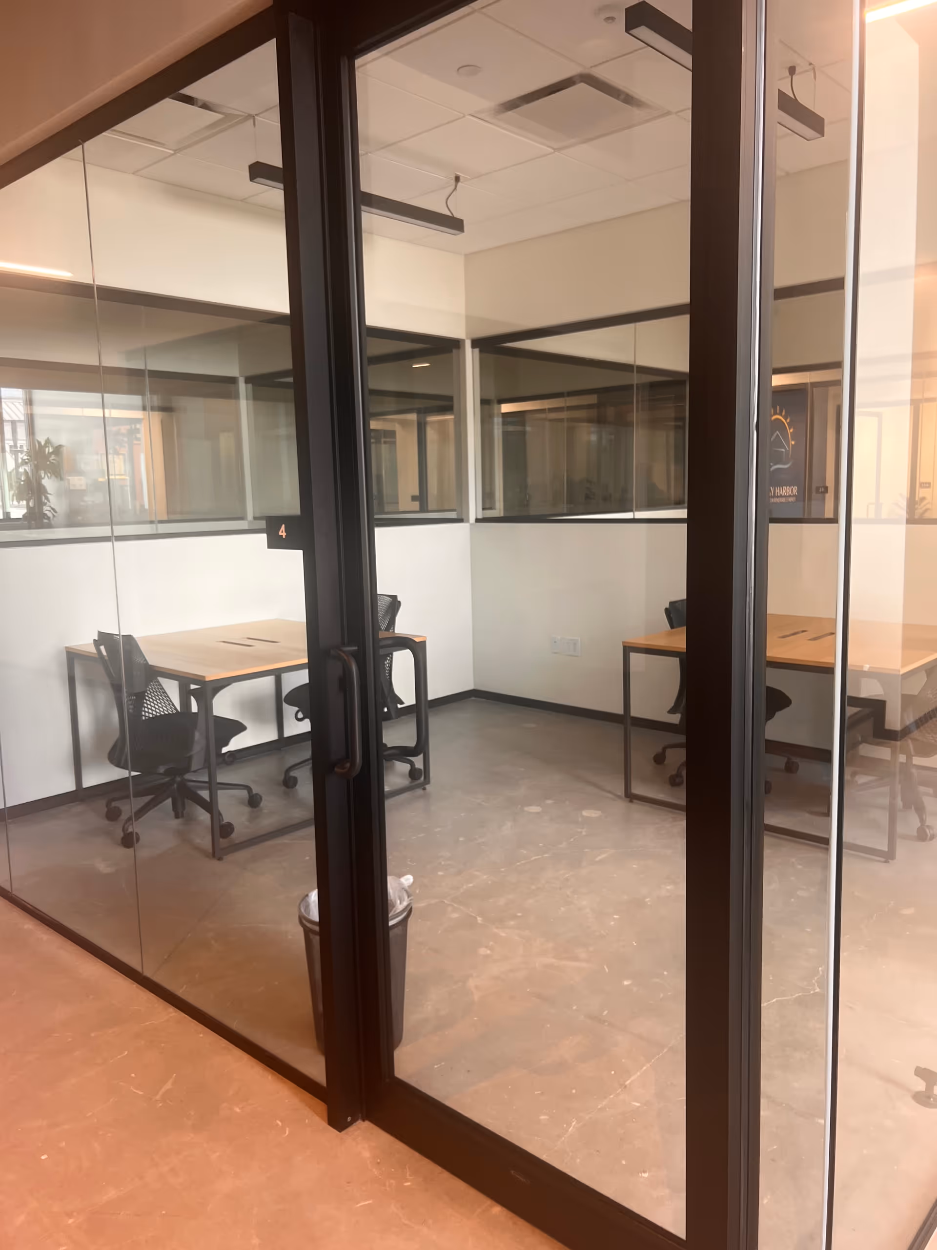 Glass-walled office area with desks and chairs inside a modern facility.