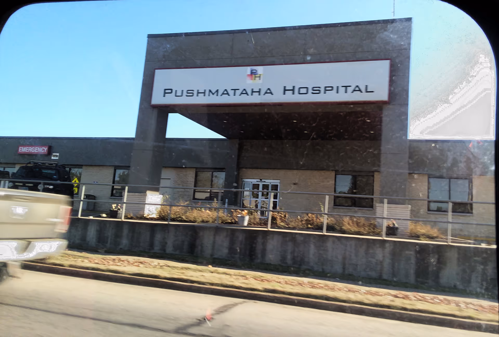 Exterior view of Pushmataha Hospital showing entrance, sign, and parking area.