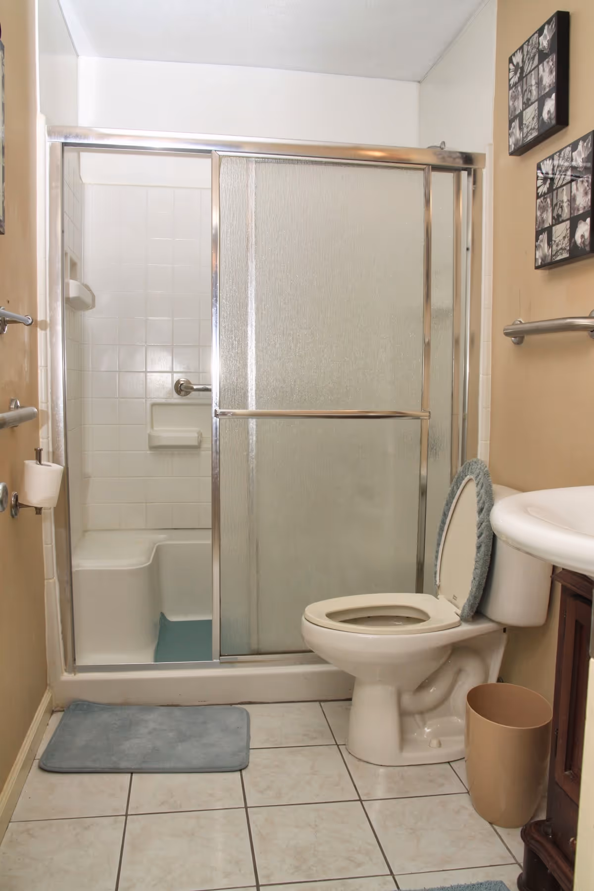 Small bathroom with shower stall, toilet, sink, and tiled floor.
