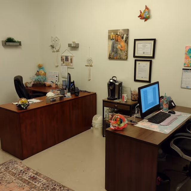 Two wooden desks with computers in a decorated administrative office.