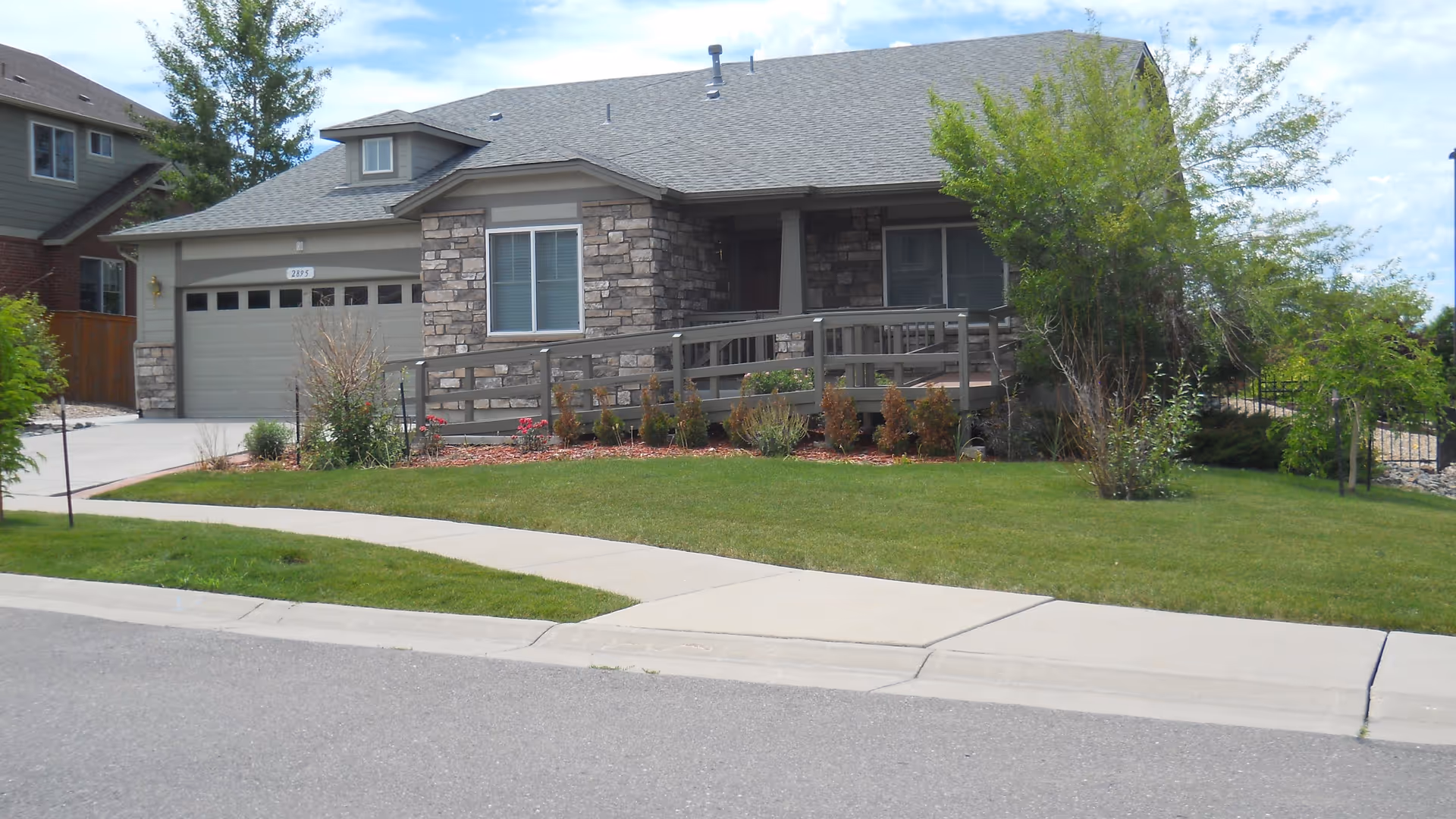 Single-story residence with stone facade, ramp, and manicured lawn.
