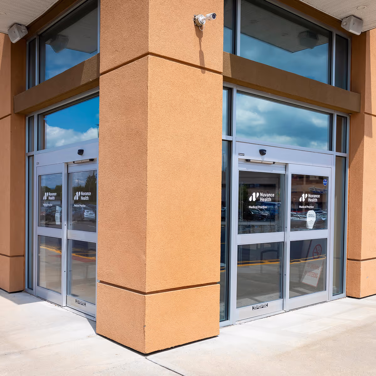 Exterior view of a peach-colored building entrance with glass doors labeled Nuvance Health.