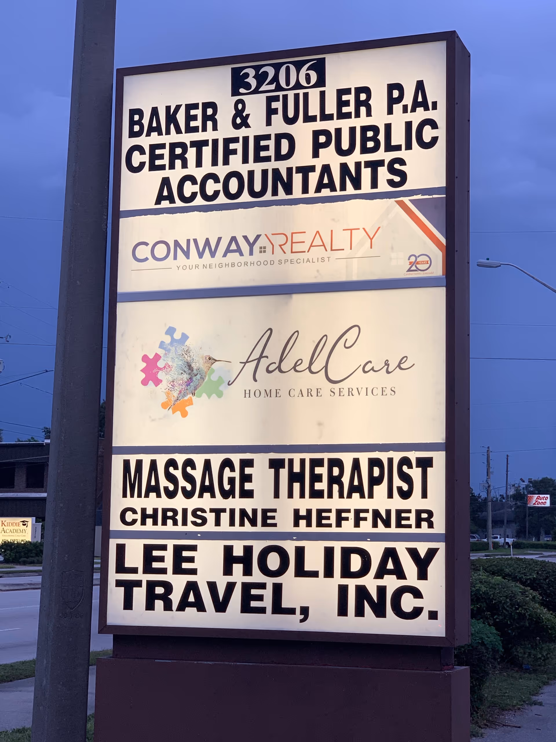 Tall outdoor signboard listing AdelCare Home Care Services alongside other business tenants.