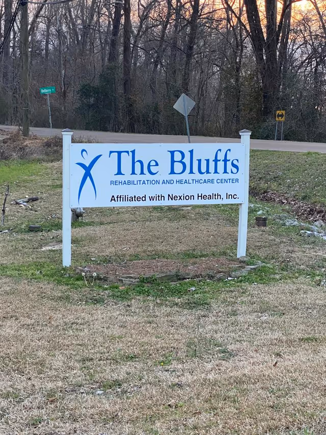 Exterior sign for The Bluffs Rehabilitation and Healthcare Center on a grassy roadside area.