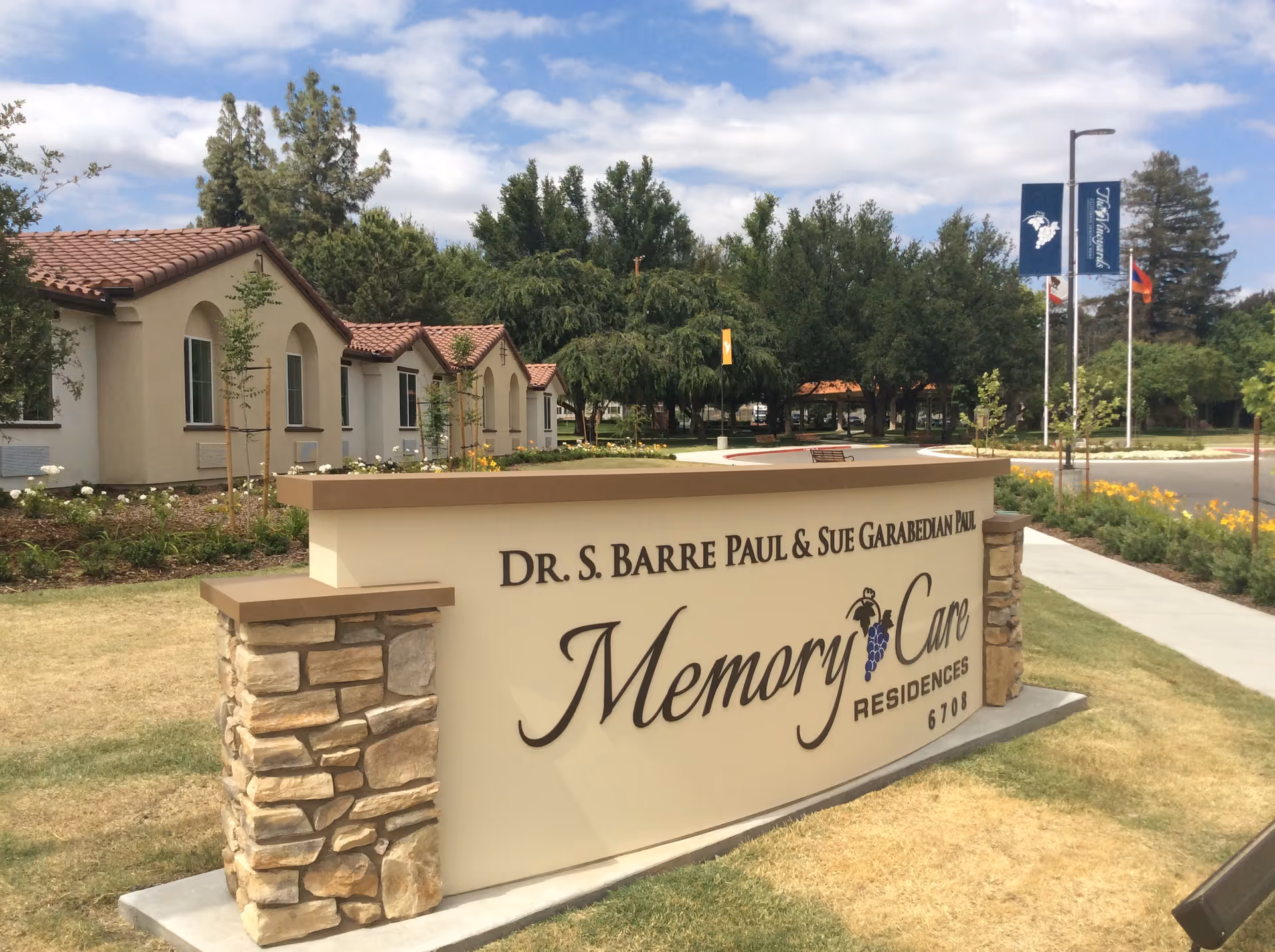 Memory Care Residences sign with stone pillars and beige, low-rise buildings nearby.