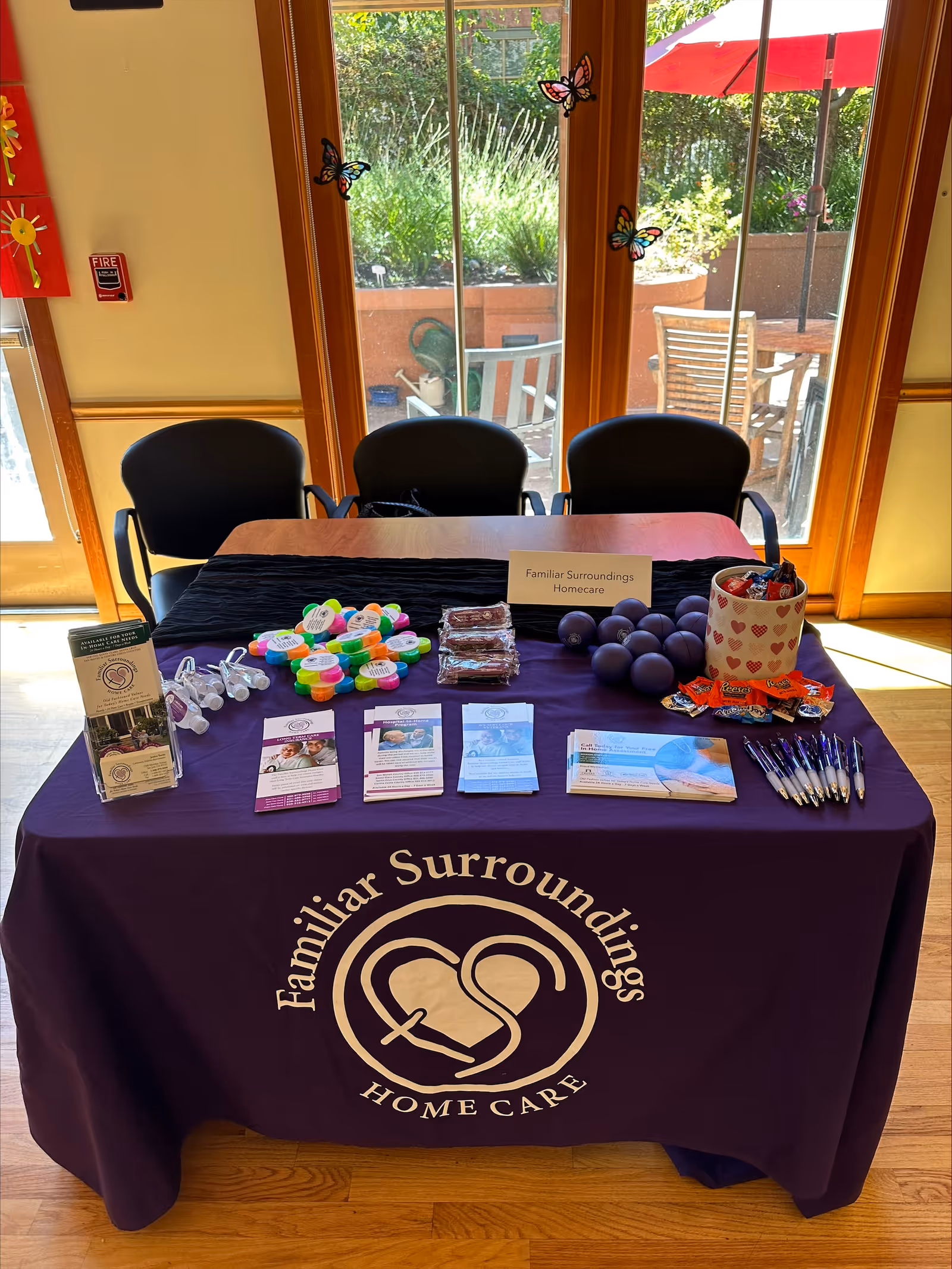 Promotional booth table for Familiar Surroundings Home Care with brochures and goodies in a sunlit interior.