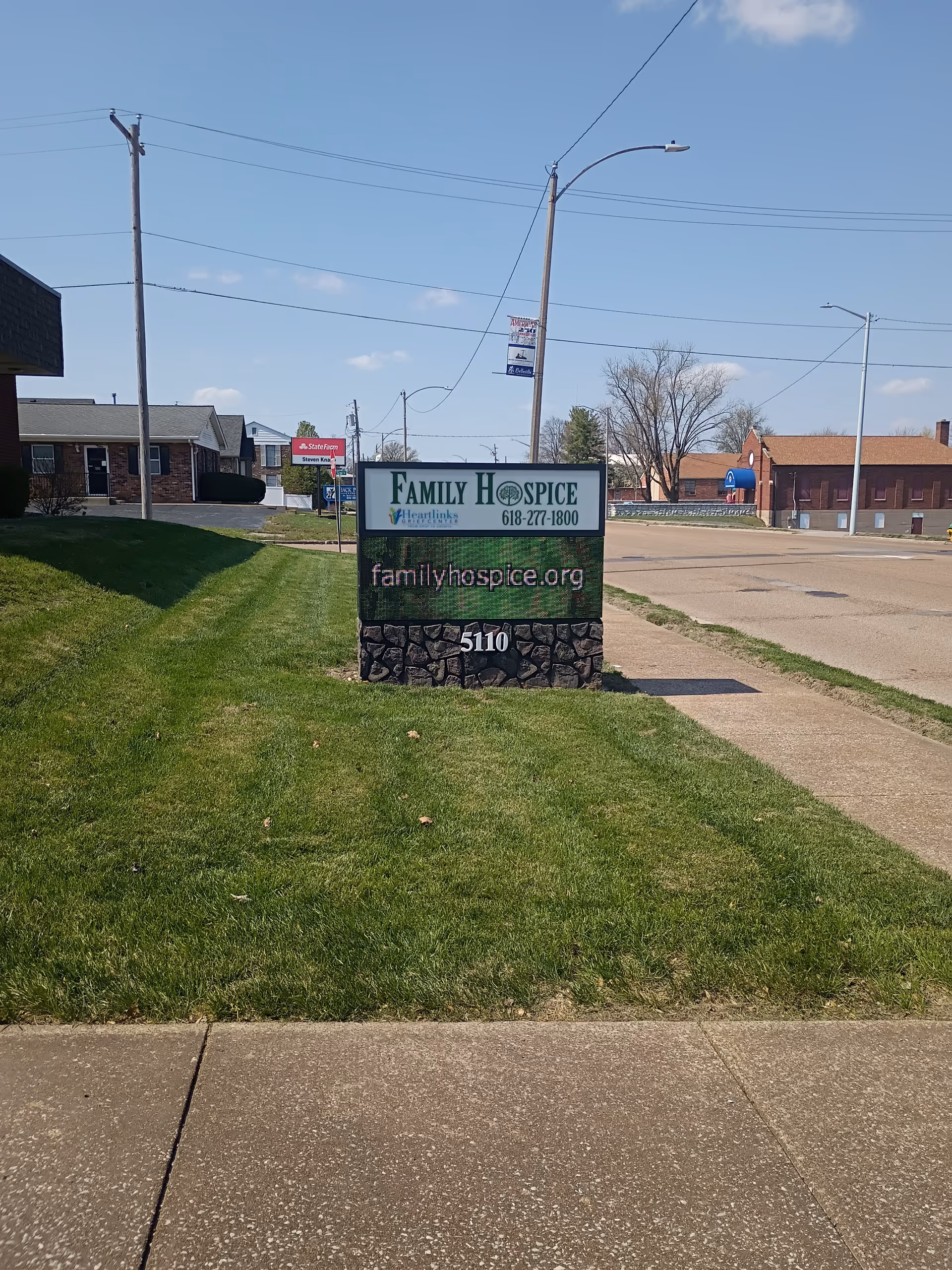 Outdoor view of a Family Hospice sign on a grassy median beside the road.