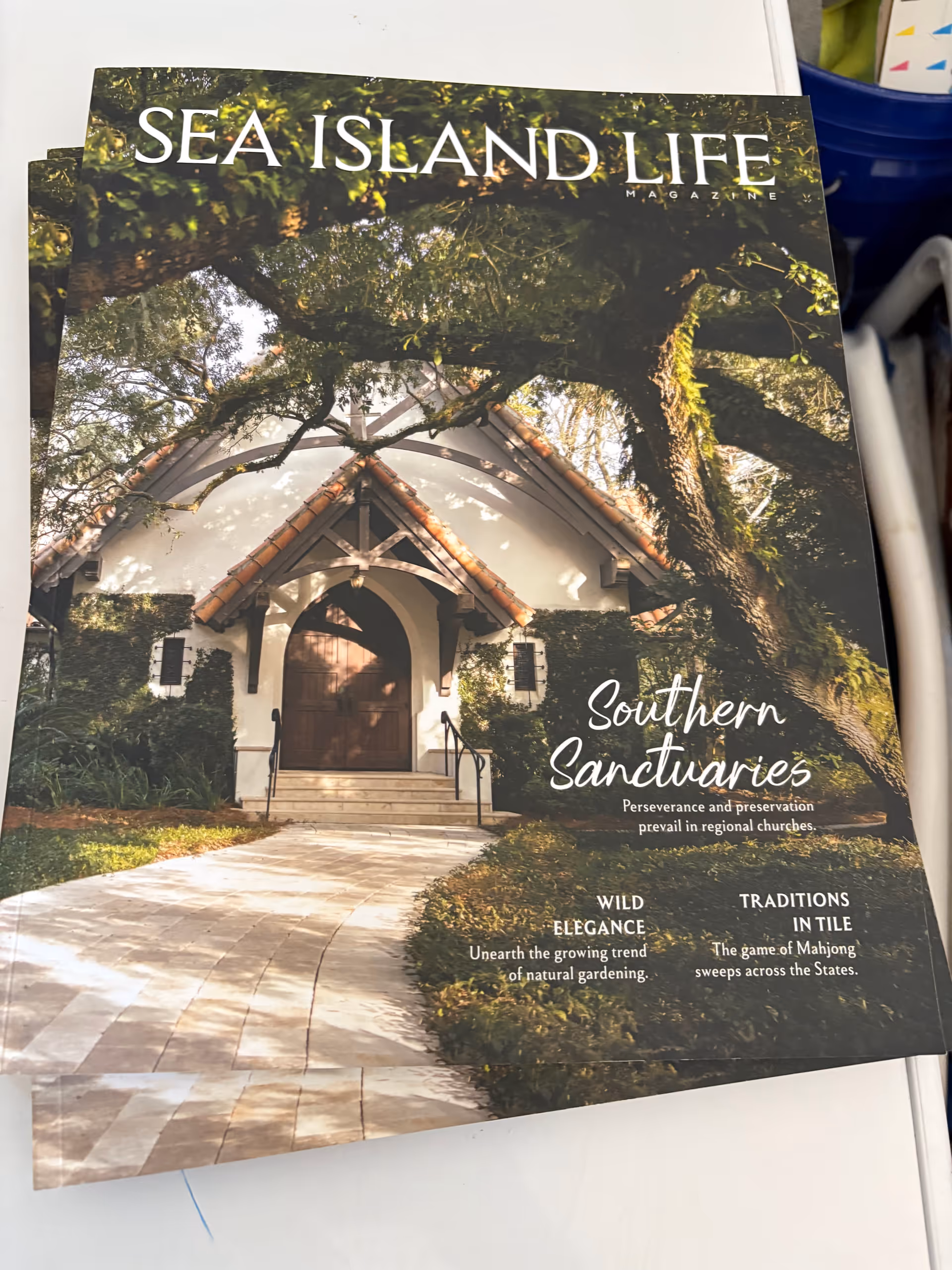 Magazine cover features a white building with arched doorway amid trees and a curved walkway.