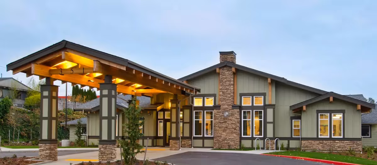 Modern senior living facility exterior with a covered entrance and stone accents.