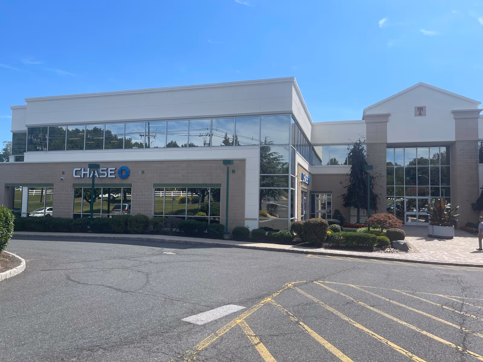 Exterior view of a modern commercial building with large glass storefront windows and blue sky.