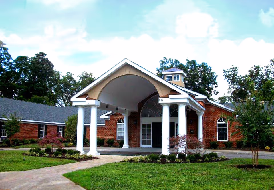 Brick senior living facility with a grand arched entrance and white columns at the front.