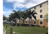 Exterior view of The Village at Schilling Farms with palm trees and a grassy lawn.