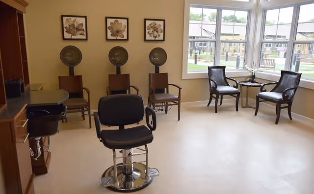 Interior salon area with a central styling chair, three hooded hair dryers, and seating.