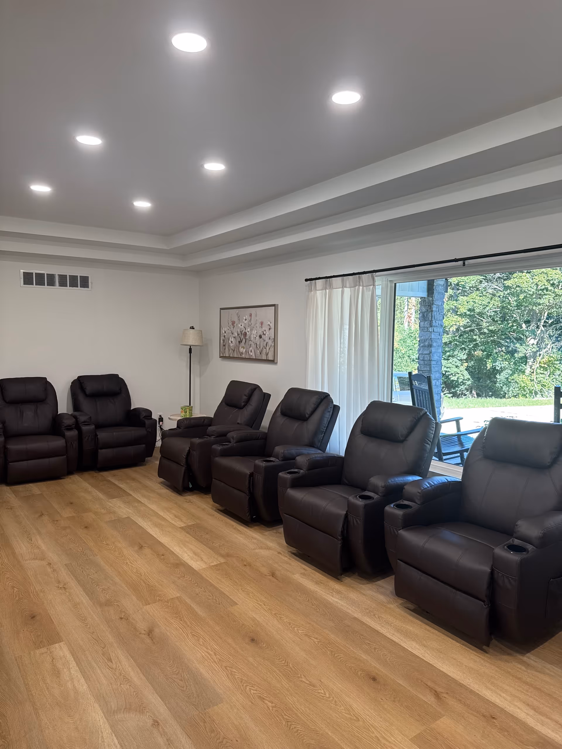 Row of brown recliner chairs in a bright living room with a sliding door to outdoors
