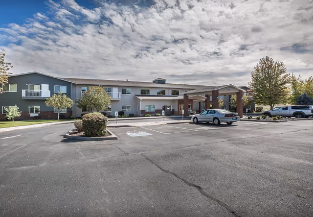 Exterior view of Sun Terrace Hermiston with parking lot and entrance canopy.