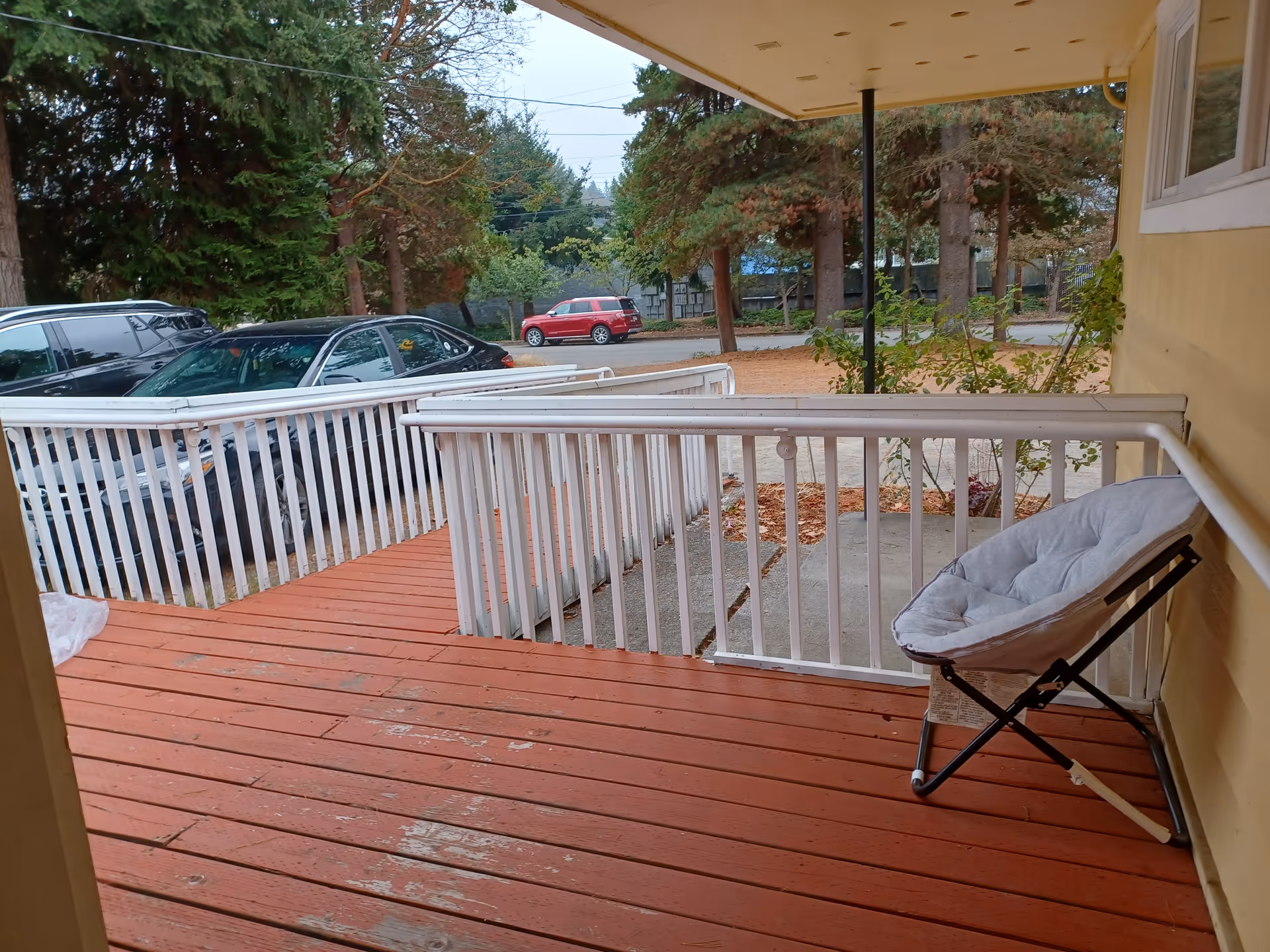 Front porch of a senior facility with a red wooden deck and chair.