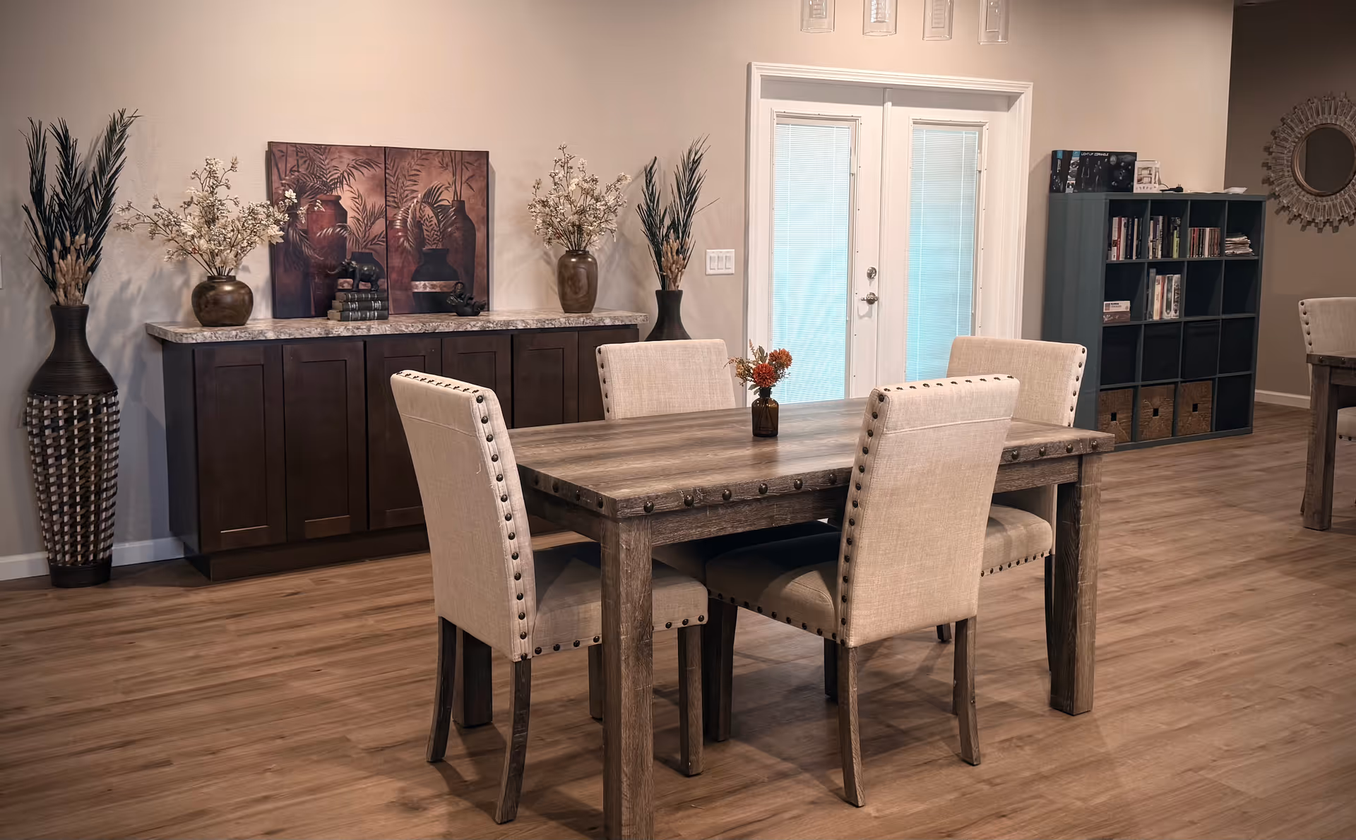A dining area with a wooden table, beige chairs, and decorative vases.