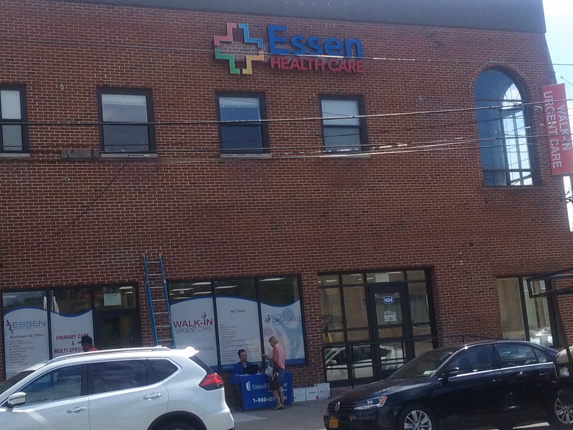 Brick medical building facade with Essen Health Care signage, windows, and parked cars.