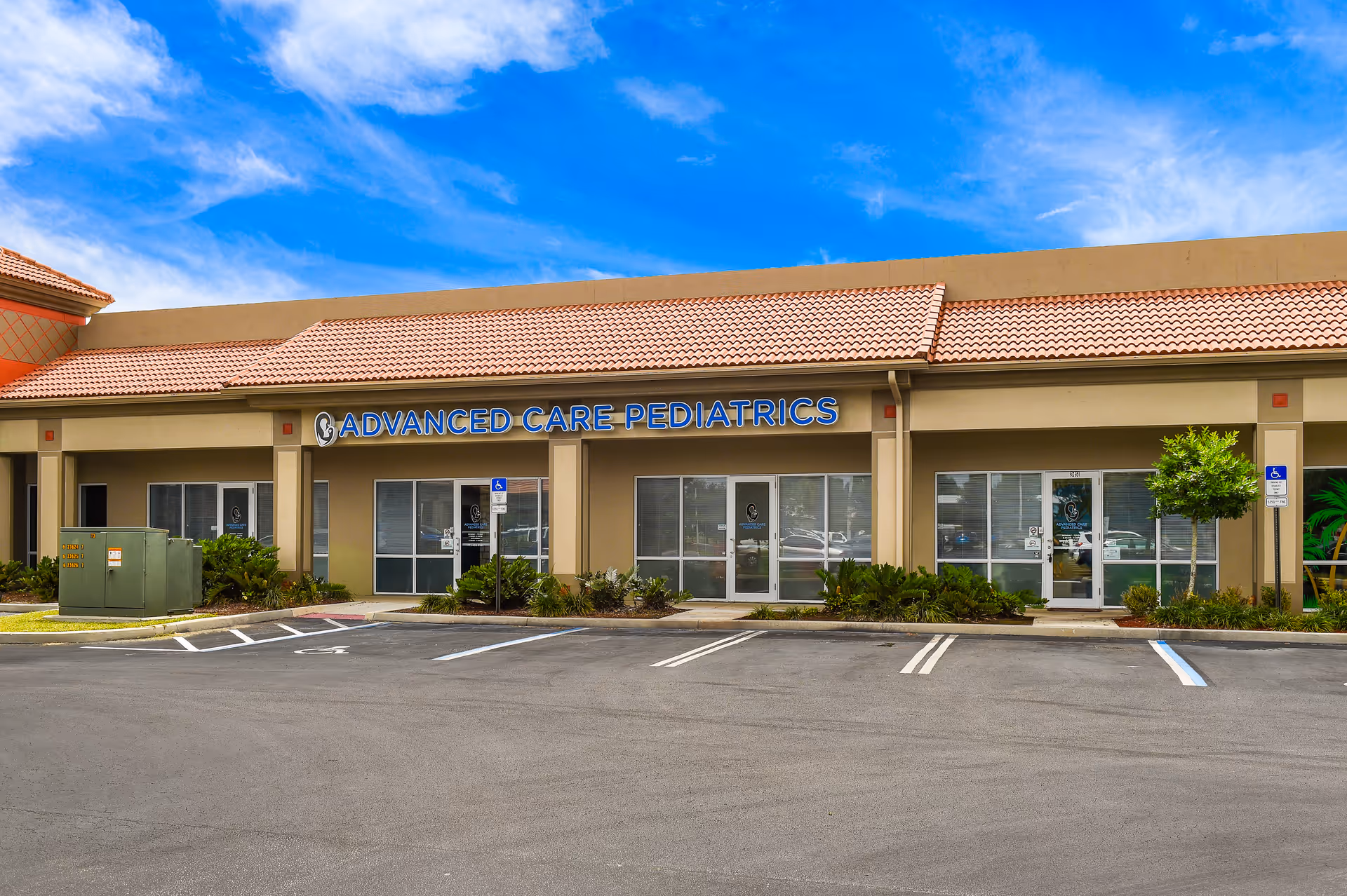 Exterior view of storefront with Advanced Care Pediatrics signage and parking lot.