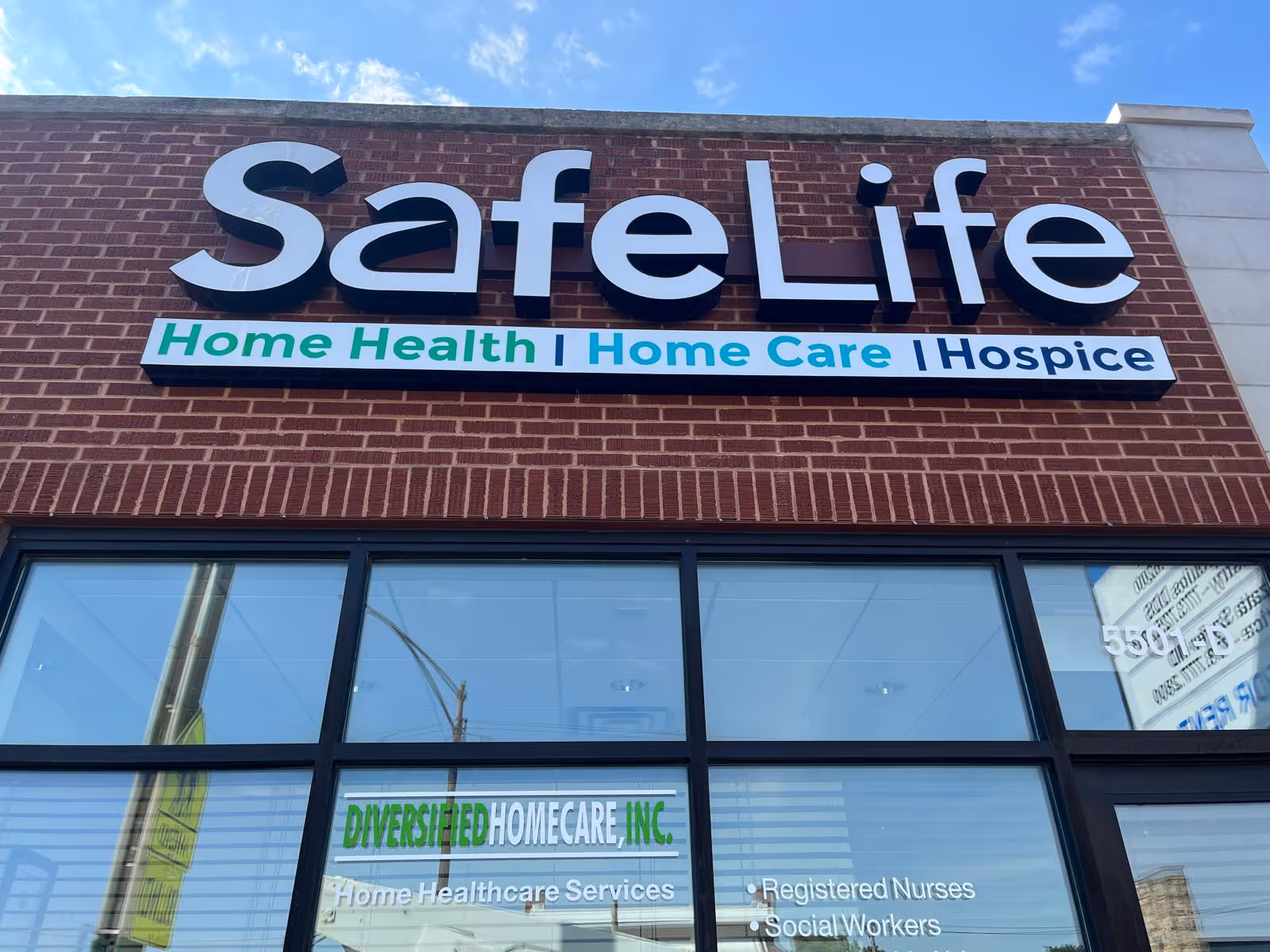 Close-up of Safe Life storefront sign on brick building with large windows.