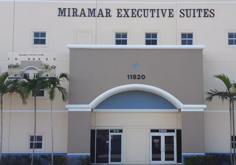 Front exterior of a beige building labeled Miramar Executive Suites with an arched entry.