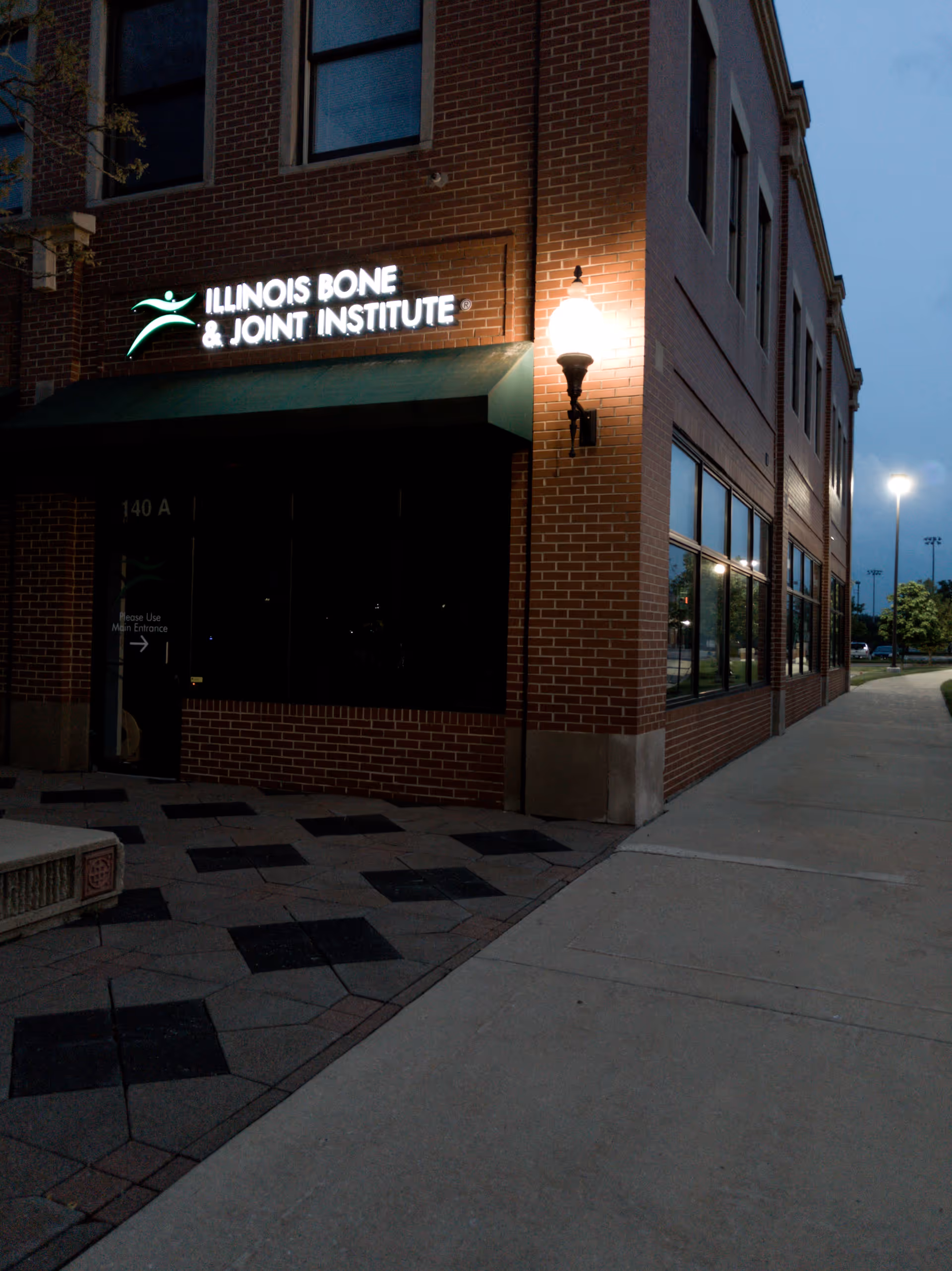 Brick clinic exterior with illuminated Illinois Bone and Joint Institute sign and entrance.