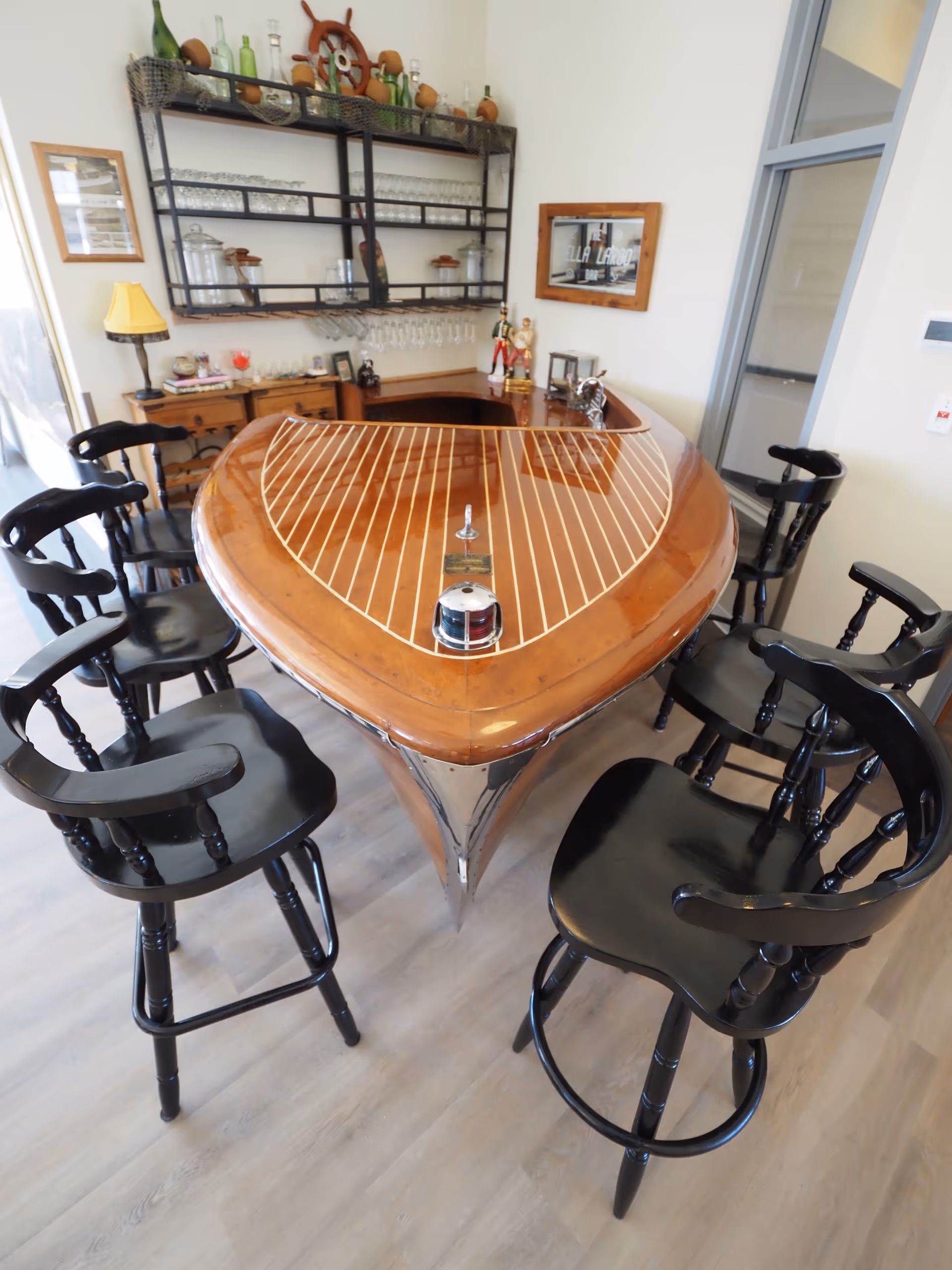 A rounded wooden bar table with high black stools in a cozy indoor lounge.