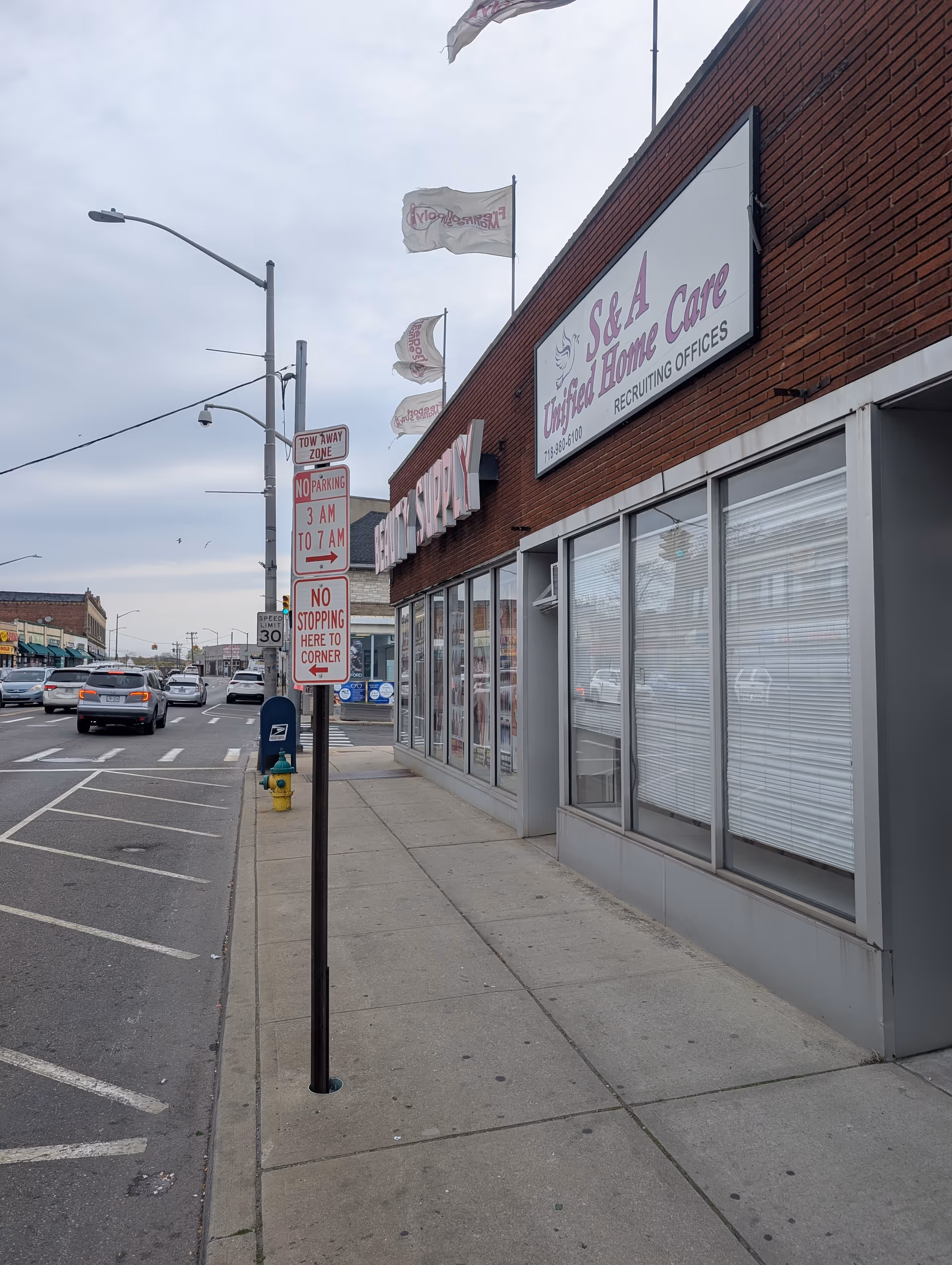 Street view of brick building with S A Unified Home Care sign and storefront windows.