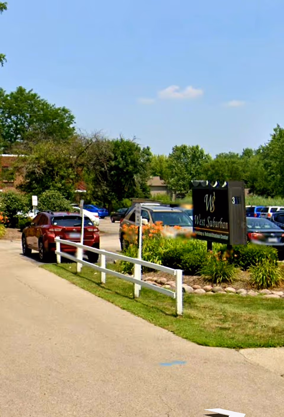 Exterior view of West Suburban Nursing and Rehabilitation Center with parking lot and landscaped entrance.