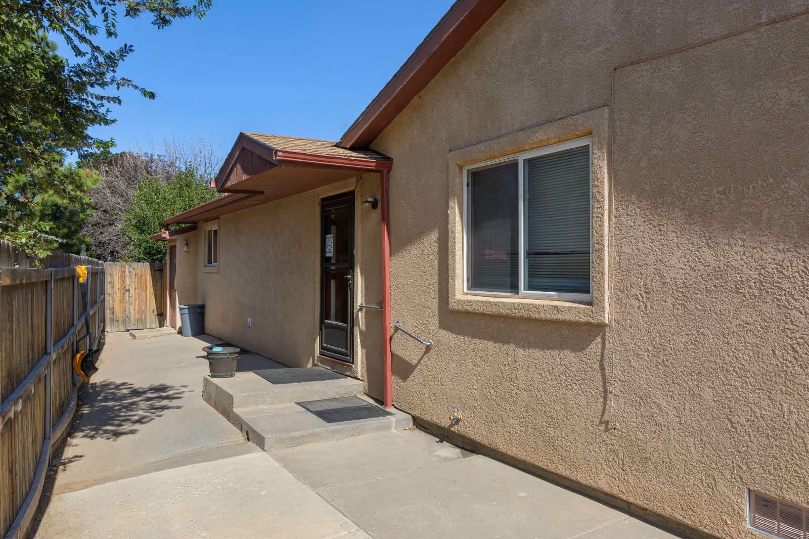 Beige exterior of a senior living facility with door, window, and concrete walkway.