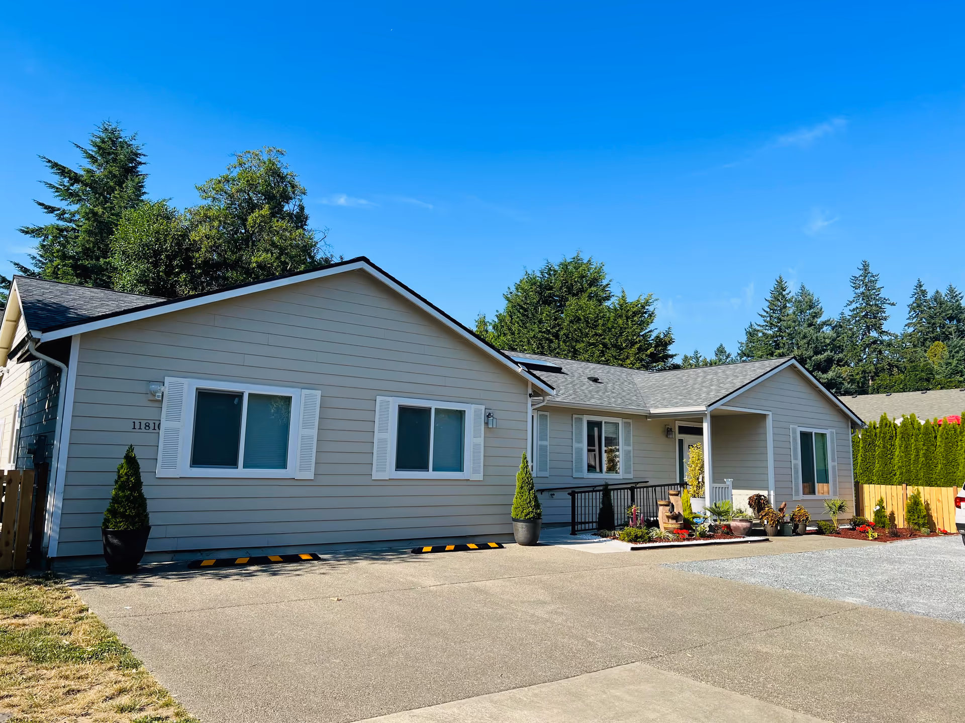 A single-story gray senior living facility with white shutters and a landscaped front.