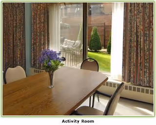 Wooden table with a vase of purple flowers in an activity room.