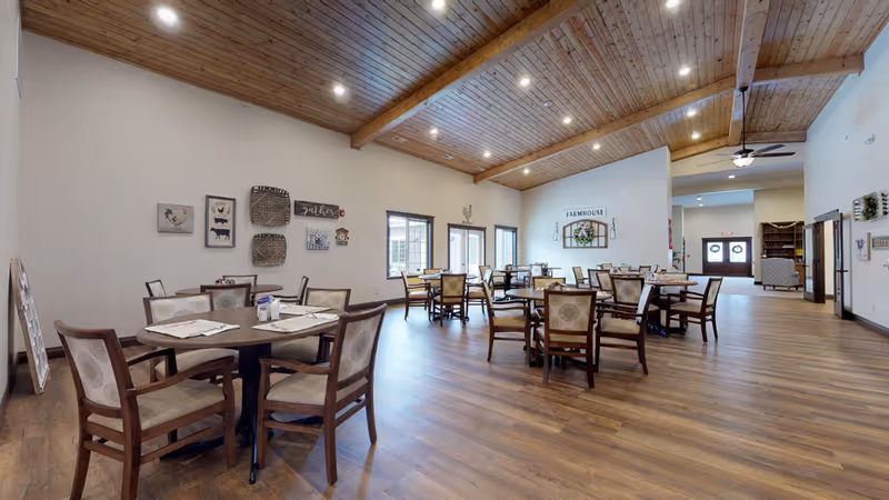 Spacious dining room in a senior living facility with wood floors and tables.