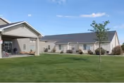Exterior view of a single-story assisted living facility with a covered entrance and manicured lawn
