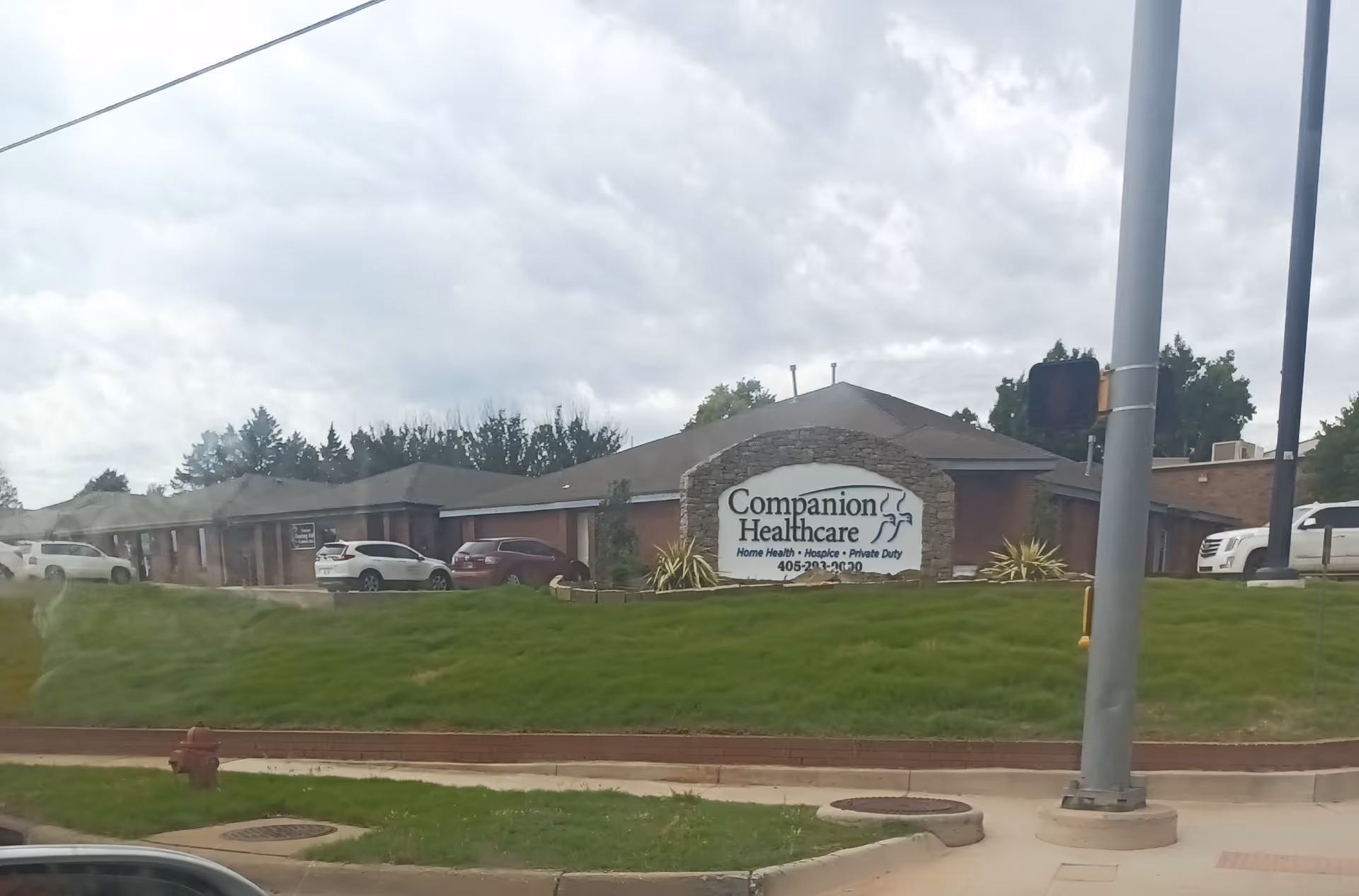 Exterior view of a healthcare facility with a stone-framed sign and parked cars.