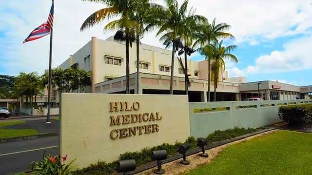 A large hospital building with a sign reading HILO MEDICAL CENTER and palm trees.