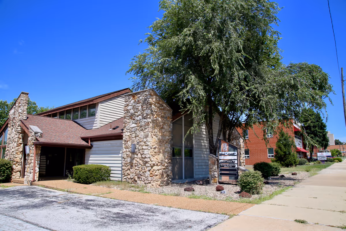 Exterior of Hospice of Southern Illinois facility with stone walls and trees.