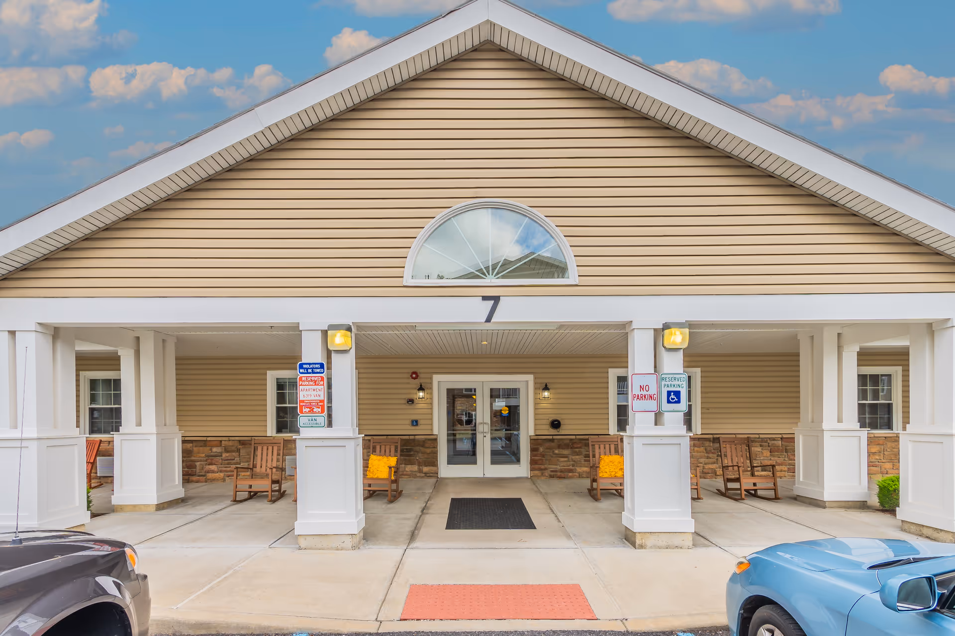 Front view of Glenmont Abbey Village entrance with a covered walkway and benches.