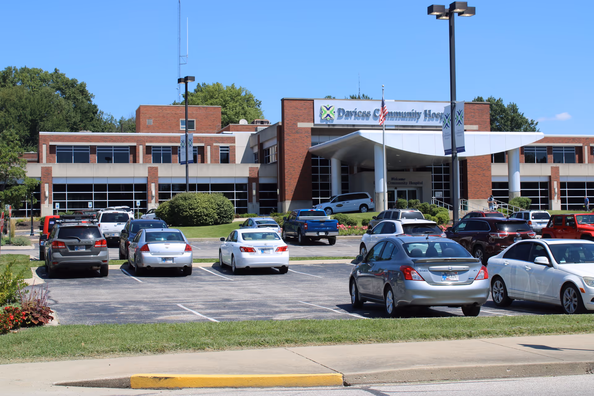 Front exterior of Daviess Community Hospital with a parking lot and clear blue sky.