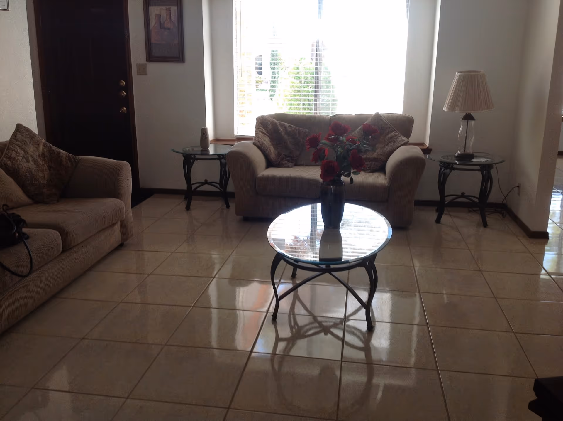 Cozy living room with beige sofas, glass coffee table, side tables, and a vase.