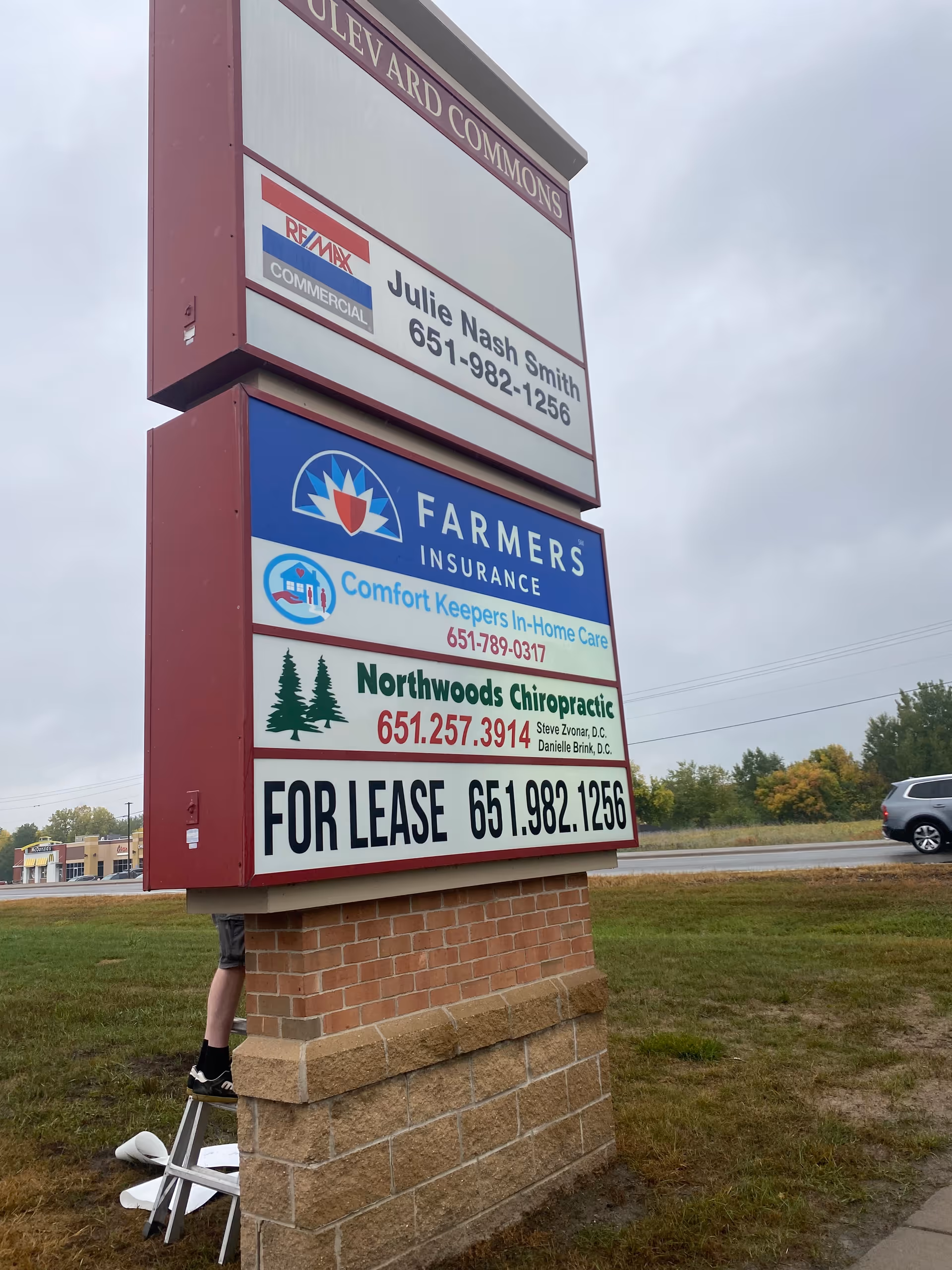 Tall outdoor sign with multiple business panels, including Comfort Keepers In-Home Care.