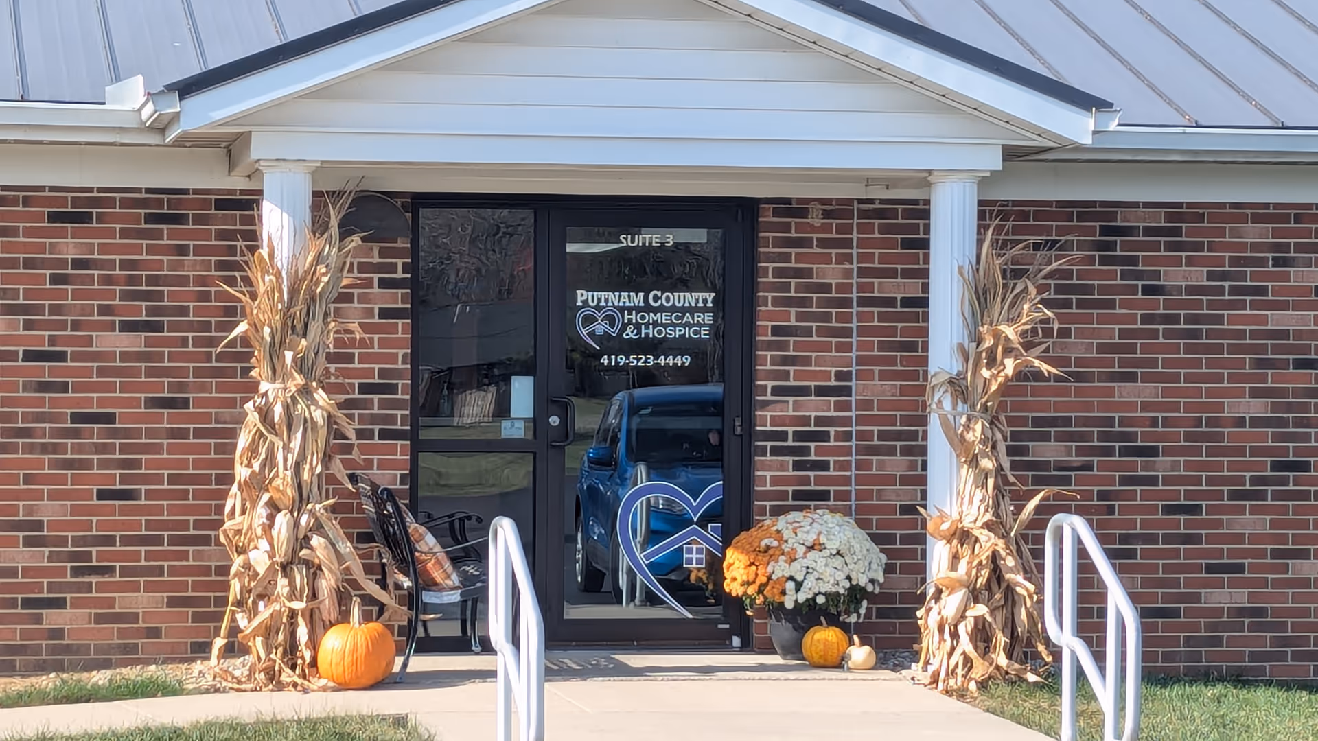 Brick building entrance with fall decorations and pumpkins, displaying Putnam County HomeCare and Hospice.