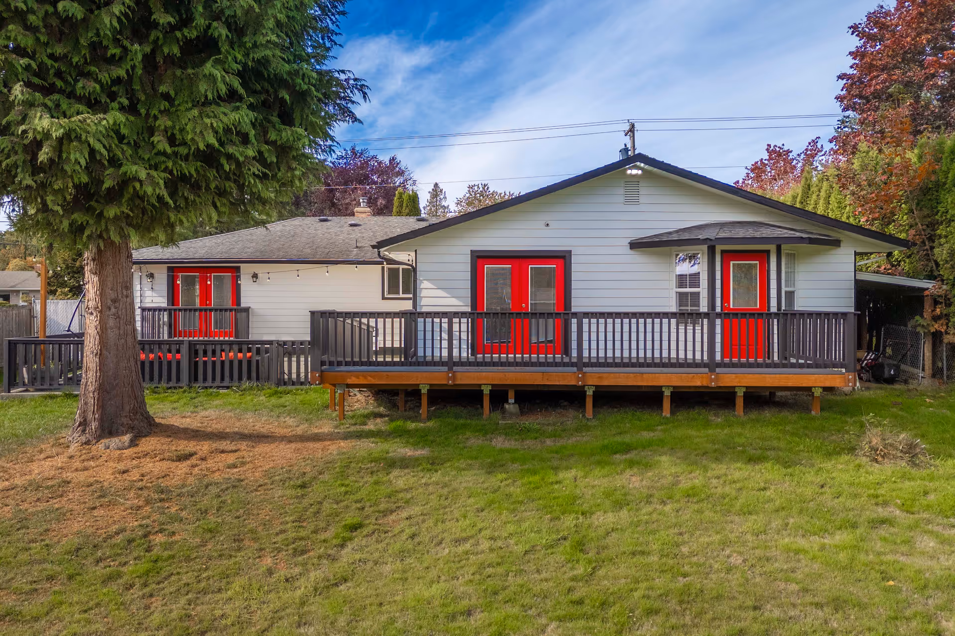 Single-story care facility with a long wooden deck, red doors, and expansive grassy lawn.